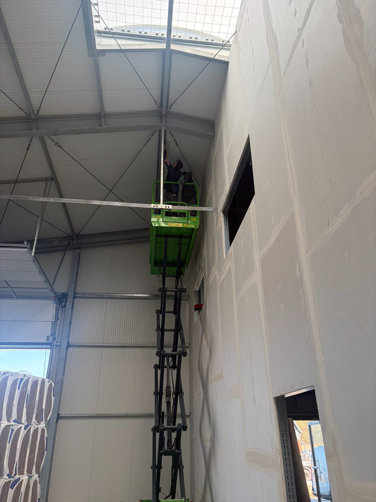 Hallenausbau: raumhohe Trockenbauwand mit Hebebühne, Montage der oberen Beplankung